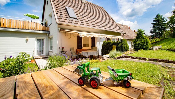 Une maison avec un toit en pente, une véranda et une terrasse en bois.