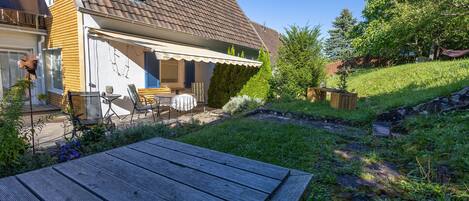 Une maison dotée d’un patio couvert, d’une terrasse en bois et d’un jardin.