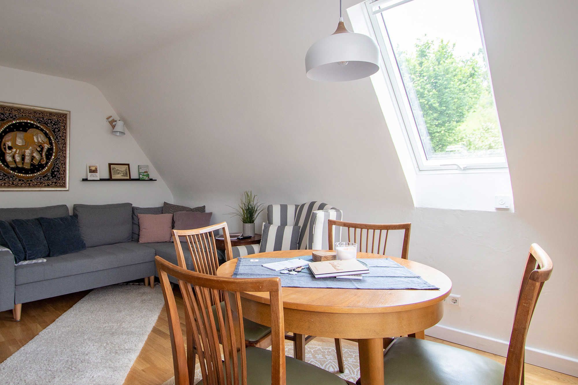 Ein Loft-Zimmer mit Esstisch, Stühlen, einer Couch und einem großen Fenster.