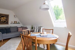 Ein Loft-Zimmer mit Esstisch, Stühlen, einer Couch und einem großen Fenster.