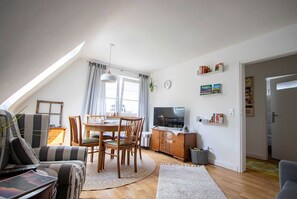 Ein gemütliches Wohnzimmer mit Essbereich, Fernseher und Bücherregal.