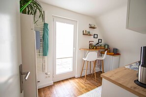 A compact kitchen with a wooden countertop, a white chair, and a small dining table.