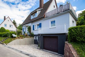 Ein zweistöckiges Haus mit Garage, Balkon und einer Treppe, die zum Eingang führt.