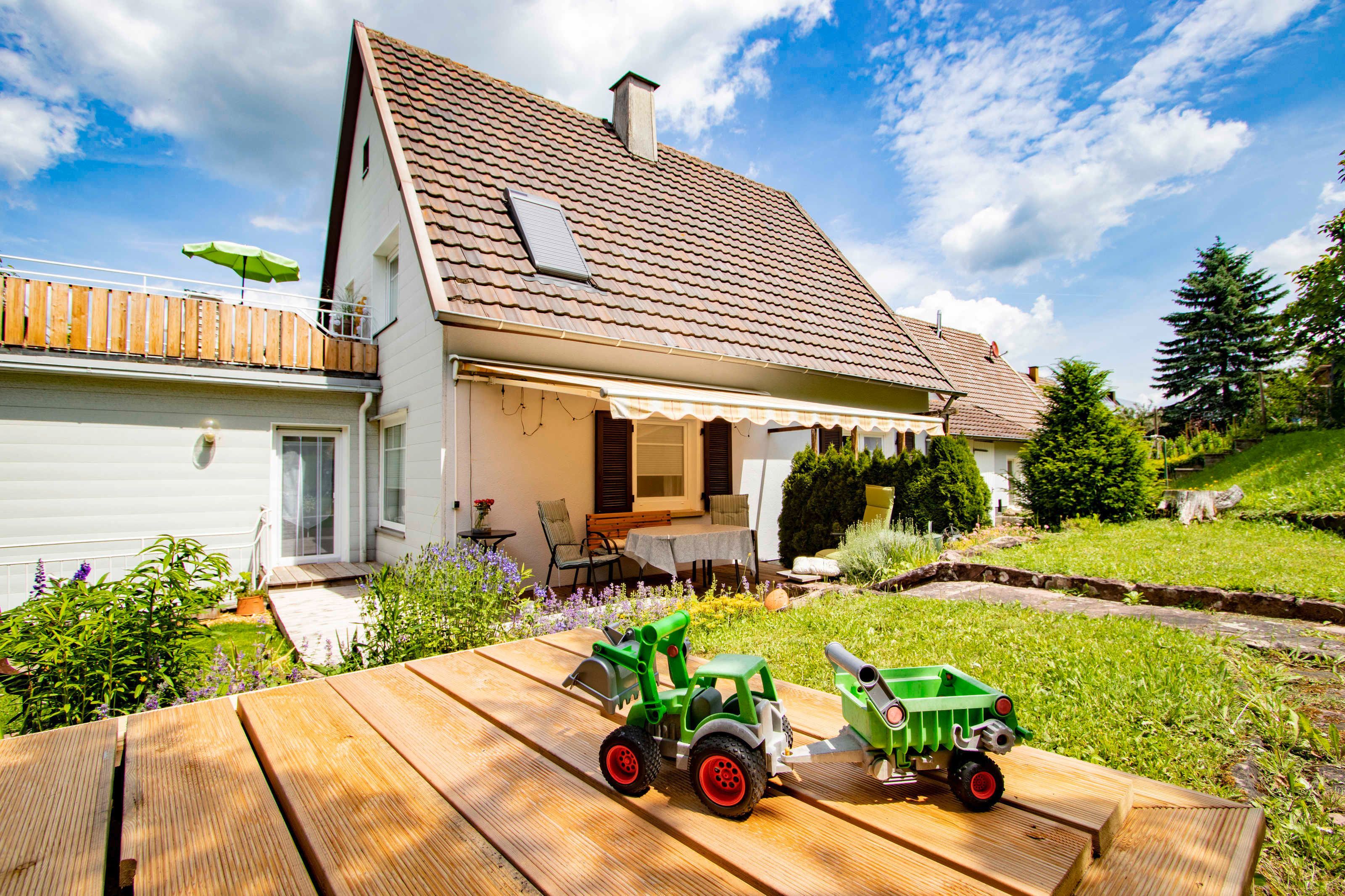 A house with a sloped roof, a covered porch, and a wooden deck.