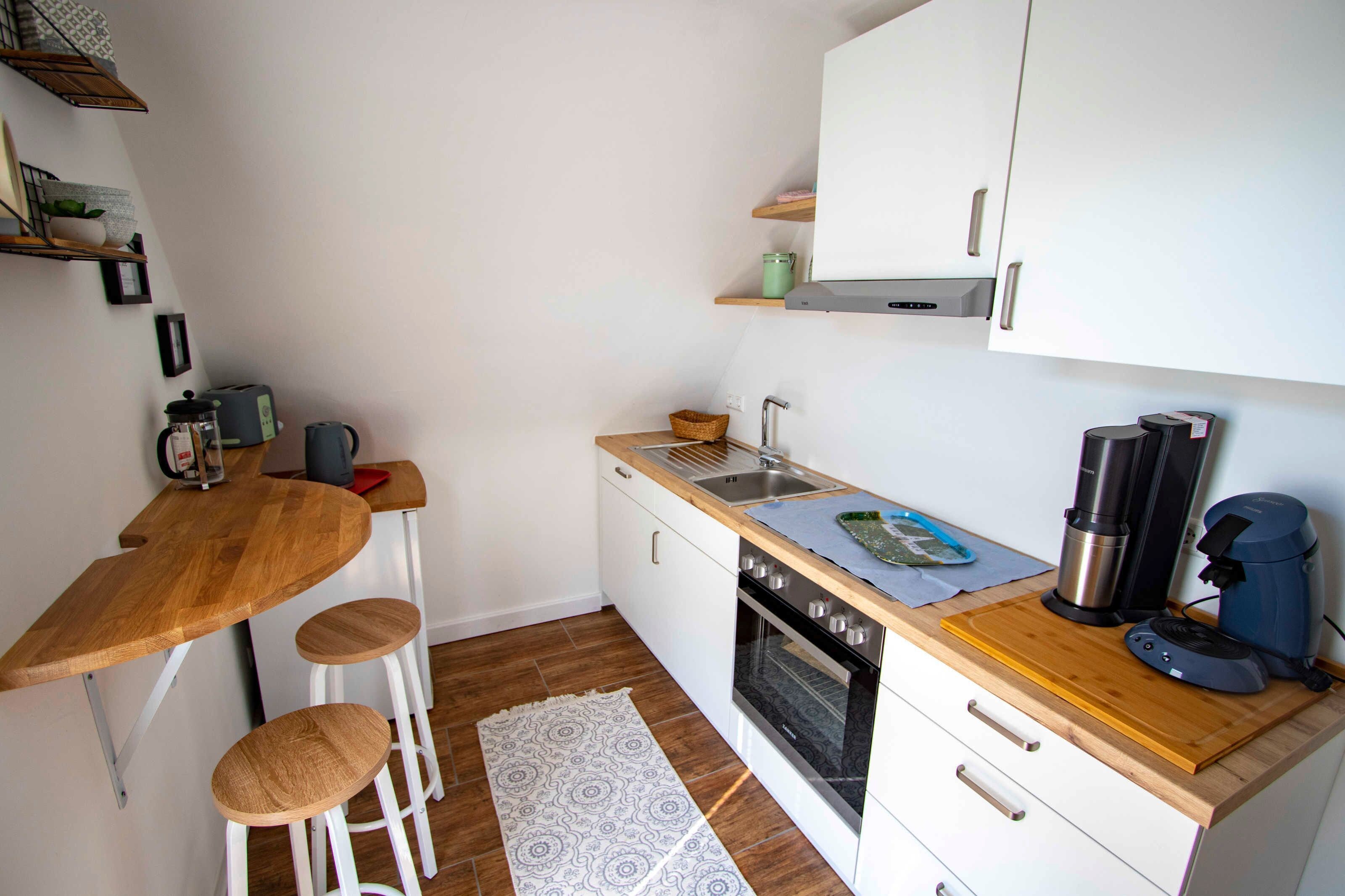 Eine kleine Küche mit einer Holz Arbeitsplatte, einem Backofen, einem Spülbecken und einer Kaffeemaschine.
