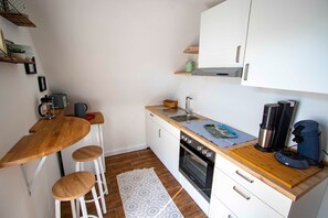 A compact kitchen with a wooden countertop, a built-in oven, a sink, and a coffee machine. - Ferienwohnung Odenwald - Paulas Ferienhaus (Buchen)