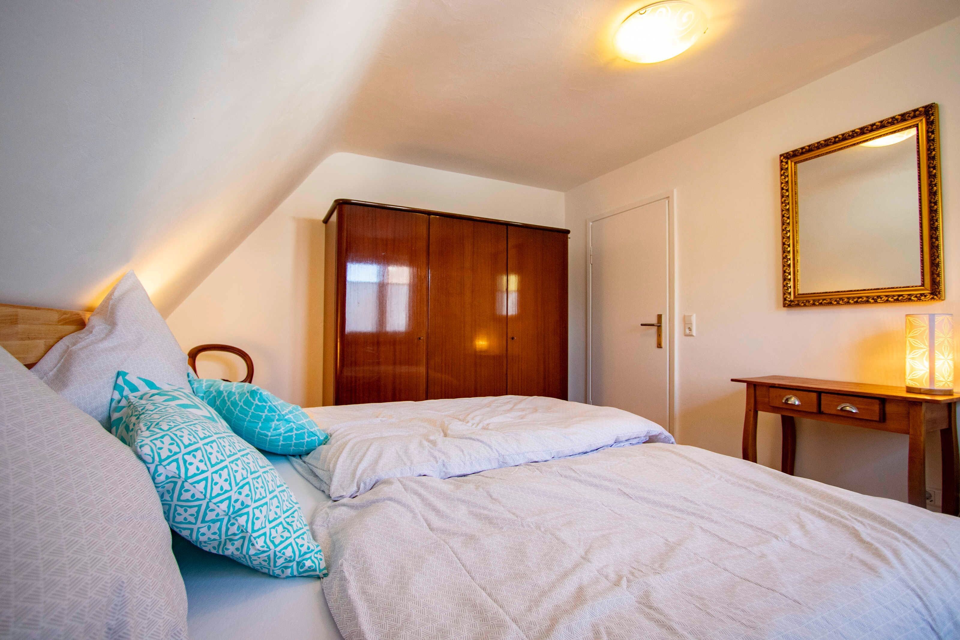 Ein Schlafzimmer mit Bett, Kissen, einem Kleiderschrank, einem Spiegel und einem Nachttisch.