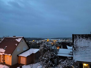 Ein Wohngebiet mit Häusern, einem mit Schnee bedeckten Baum und fernen Lichtern.