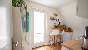 Une cuisine compacte avec un plan de travail en bois, une chaise blanche et une petite table à manger.