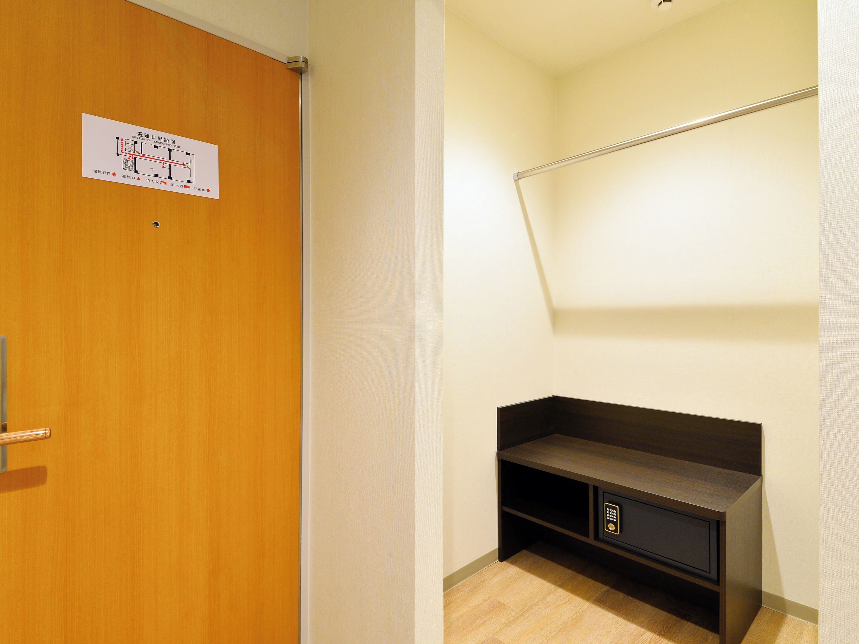 A room with a wooden door, a wall-mounted shelf, and a light fixture.