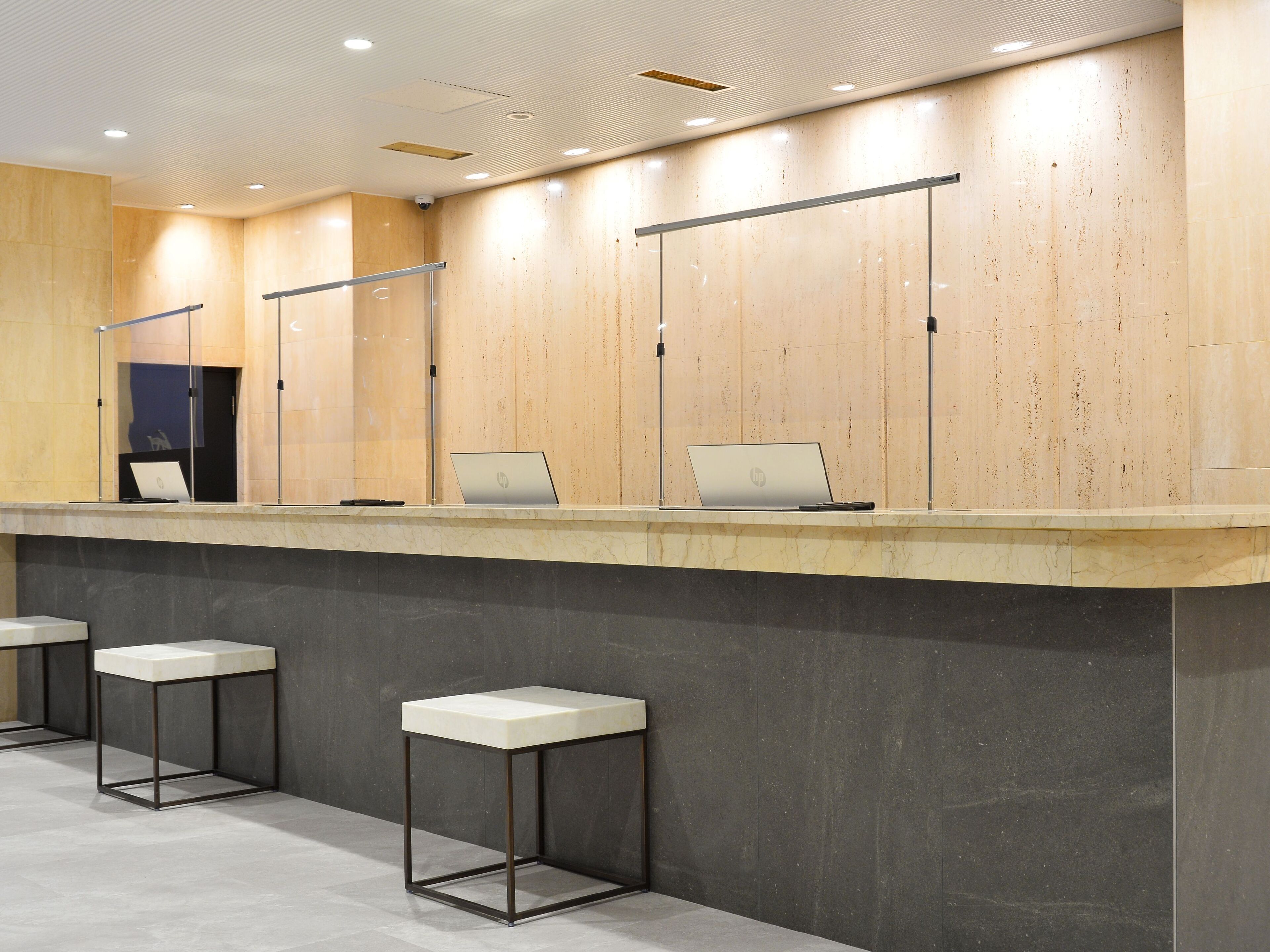 A modern reception area with a marble counter, two bar stools, and two HP laptops on the counter.