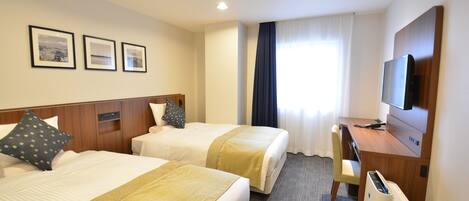 A hotel room with two beds, a desk, a chair, a TV, and a window with curtains.