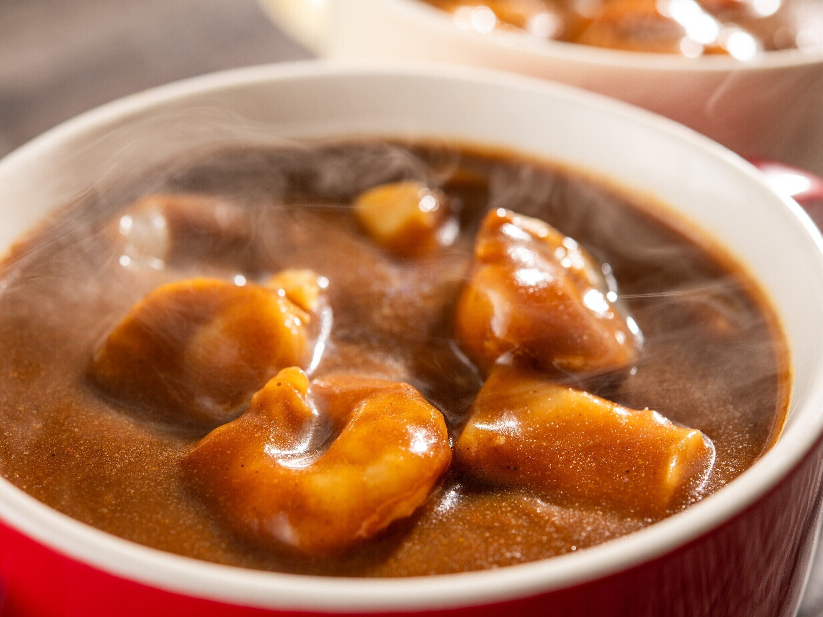 A bowl of soup with chunks of meat and vegetables in a clear broth.