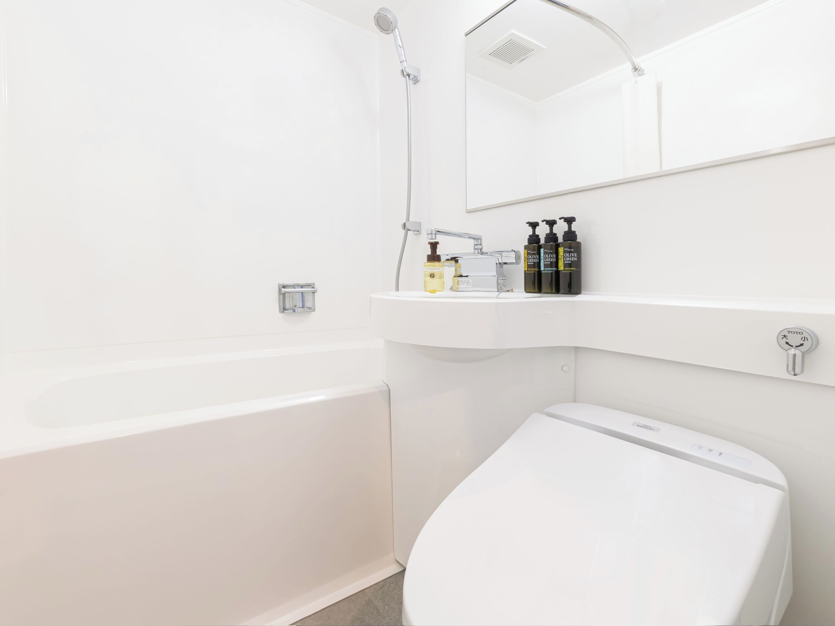 A modern bathroom with a white bathtub, a toilet, and a sink area with toiletries.