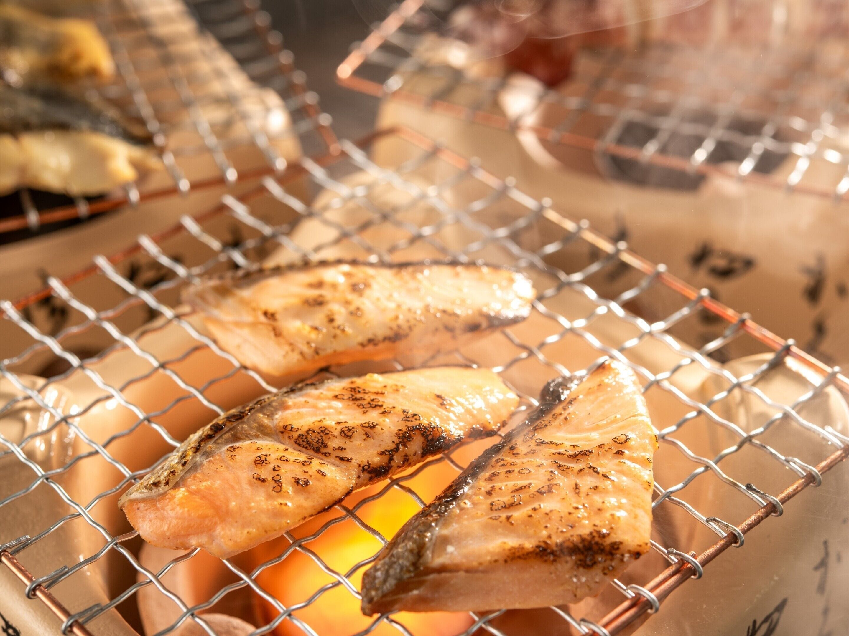 Poisson grillé sur une grille au-dessus d’une flamme nue.