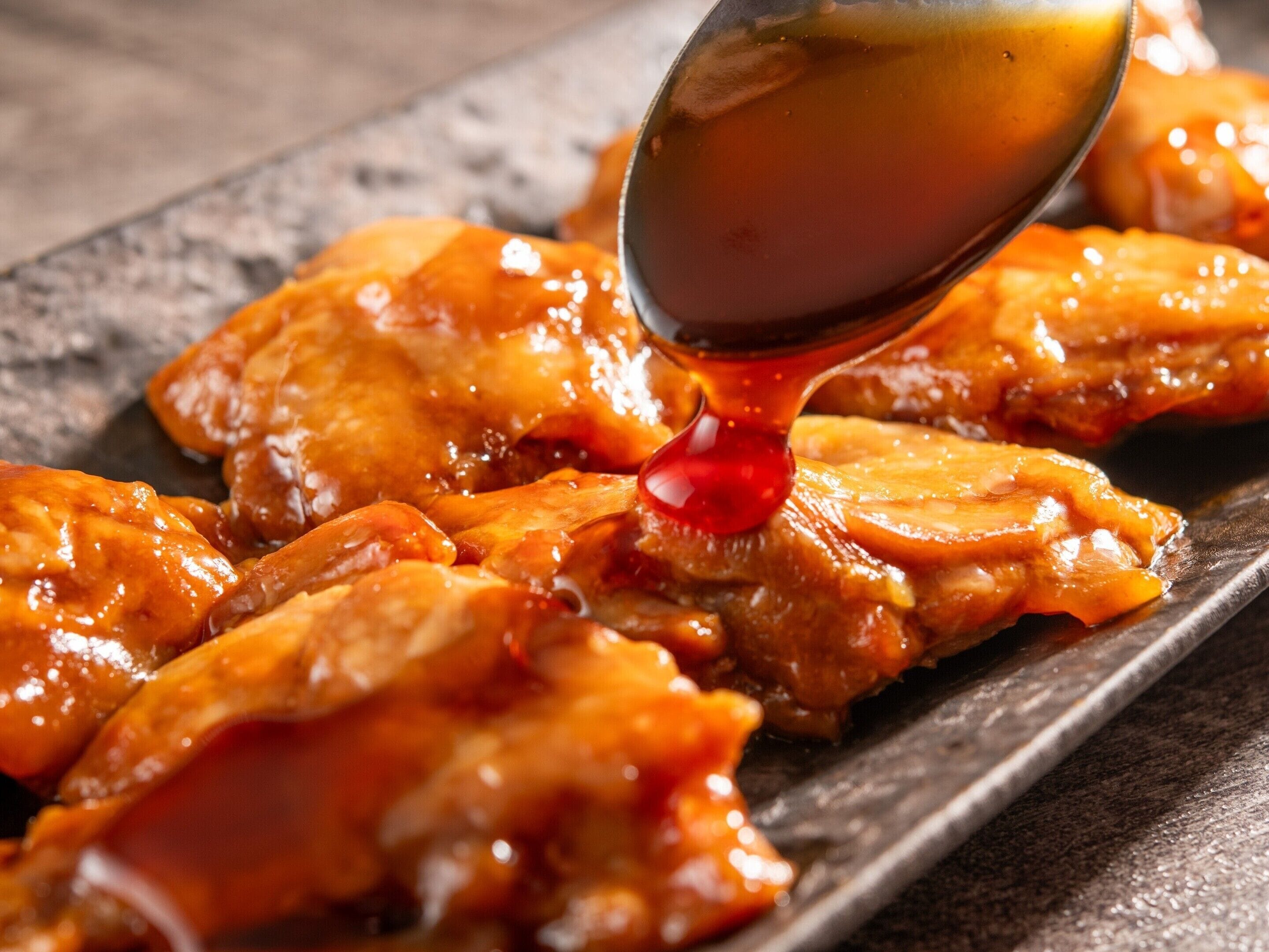 A close-up of a dish with a glossy, caramelized sauce being poured over it.