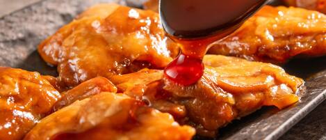 A close-up of a dish with a glossy, caramelized sauce being poured over it.