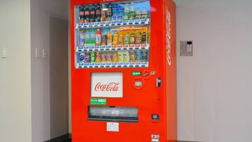 A red Coca-Cola vending machine with multiple drink options and a payment slot.