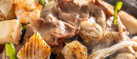 A close-up of grilled seafood, including shrimp and scallops, with visible char marks.