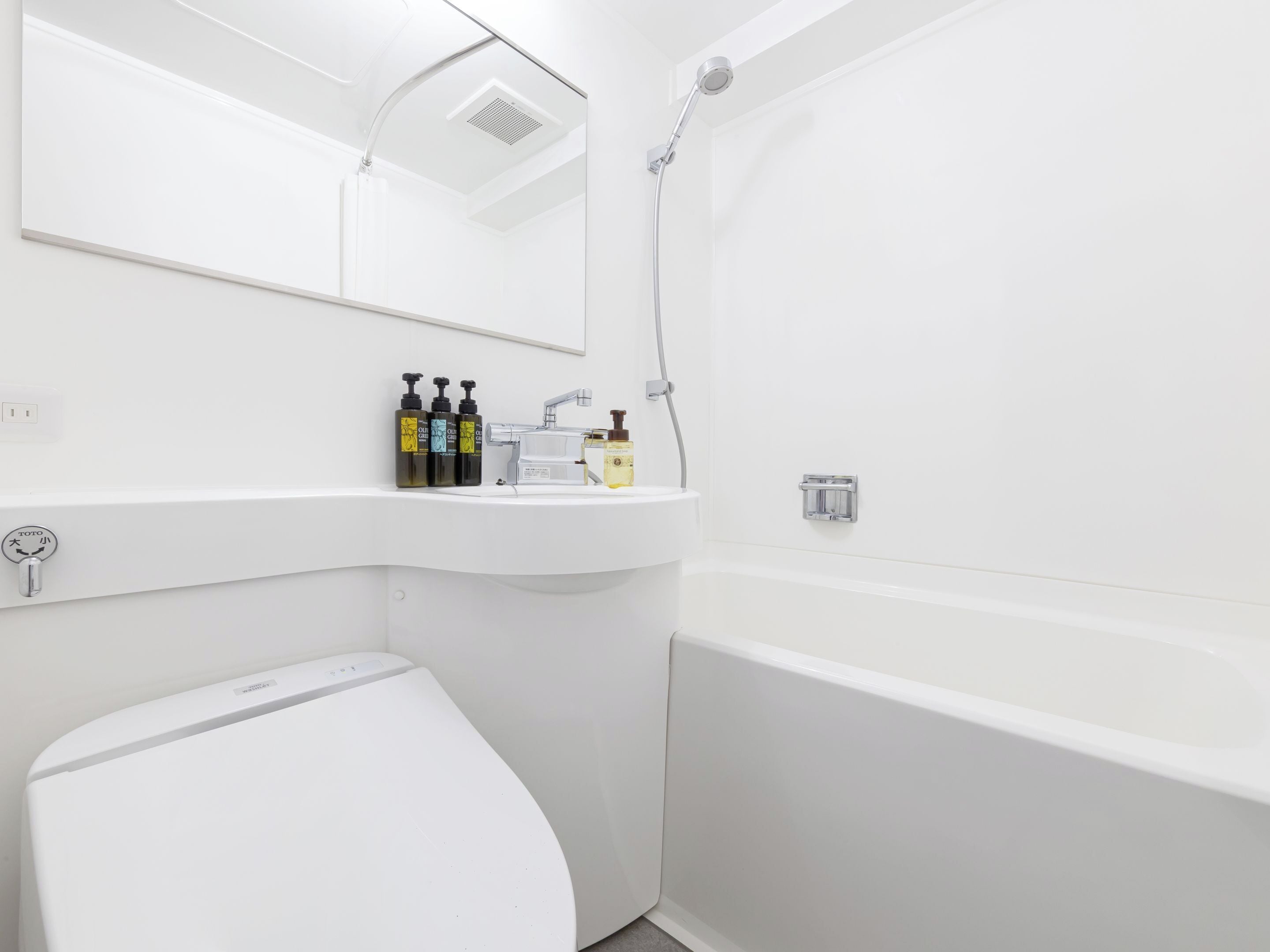 A modern bathroom with a white sink, mirror, and shower.
