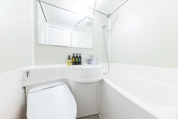 Une salle de bain moderne avec un lavabo blanc, un miroir et une baignoire. On peut voir des articles de toilette sur le comptoir du lavabo.