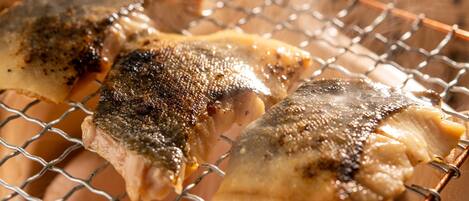 Tres piezas de pescado sobre una rejilla, probablemente a la parrilla.