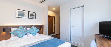A hotel room with a bed, a television, and a door.