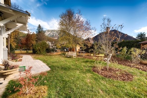 Un jardín con patio, bancos y montañas al fondo.