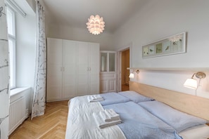 A bedroom with a bed, a wardrobe, a hanging light fixture, and a framed picture on the wall.