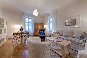 Una sala de estar con sofá, una silla, una mesa de comedor y una lámpara.