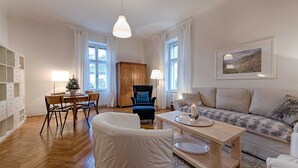 Una sala de estar con sofá, una silla, una mesa de comedor y una lámpara.