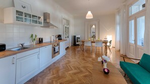 Una cocina moderna con armarios blancos, encimera de madera y suelo con estampado de espiga.