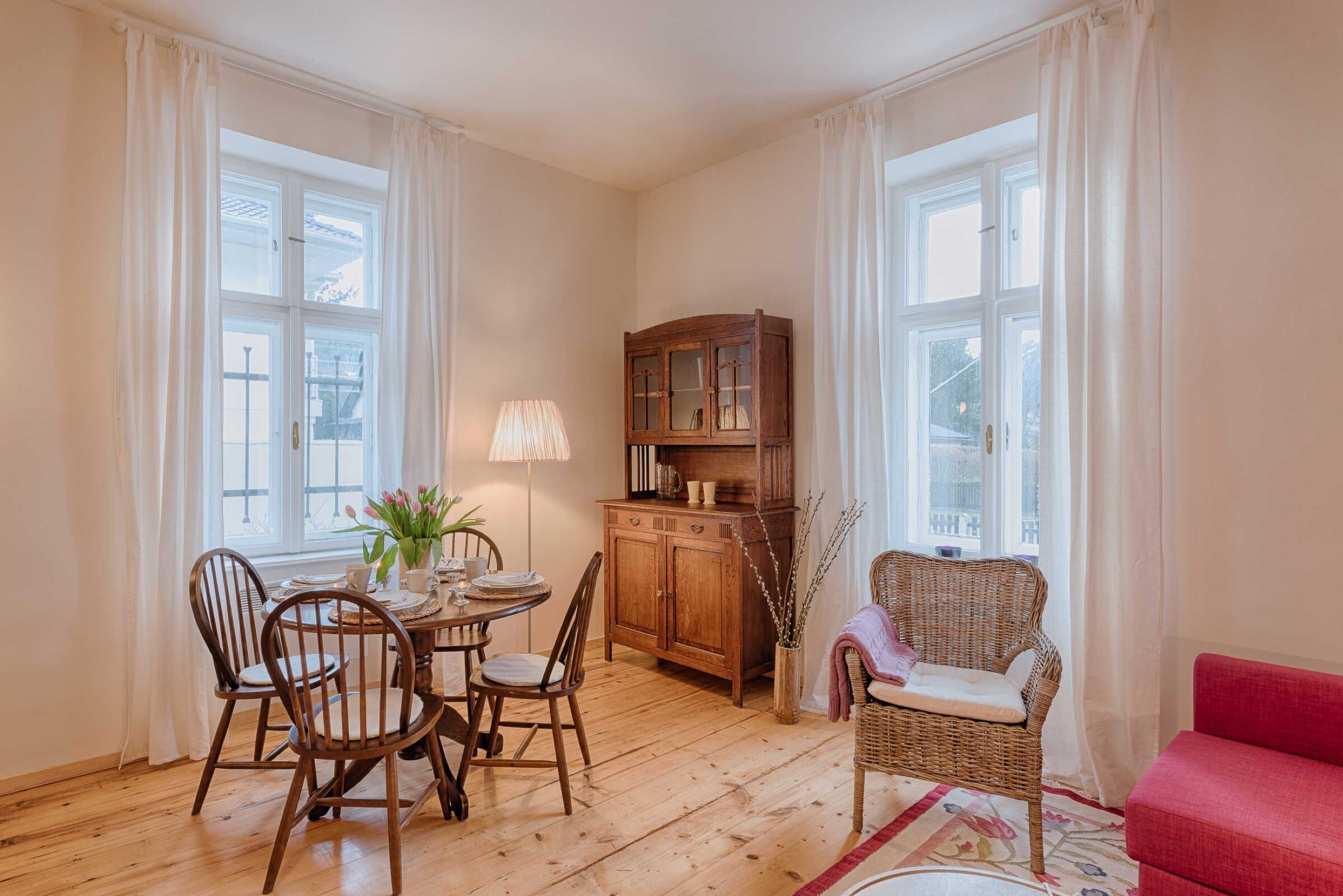 A dining area with a wooden table and chairs, a cabinet, and a wicker chair.