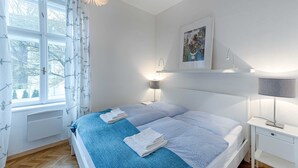 Une chambre à coucher avec un lit, une table de chevet, une lampe et une fenêtre avec des rideaux.