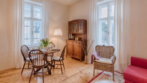 Un coin repas avec une table et des chaises en bois, un buffet et un fauteuil en osier.
