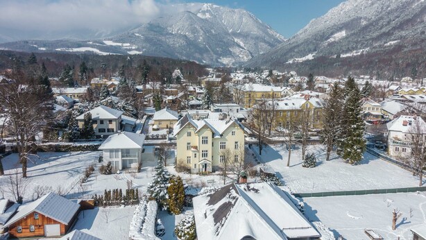 Une ville recouverte de neige, avec des maisons et des montagnes en arrière-plan.