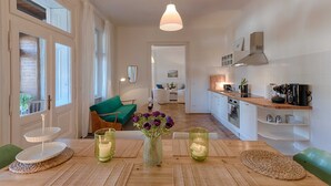 Une cuisine moderne avec un coin repas, comprenant une table en bois, un luminaire suspendu et une vue sur le salon.