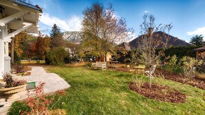 Un jardin avec une terrasse, des bancs et une vue sur les montagnes en arrière-plan.