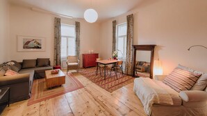 Un salon comprenant un canapé, une table basse, une table à manger avec des chaises, une commode rouge et un miroir.