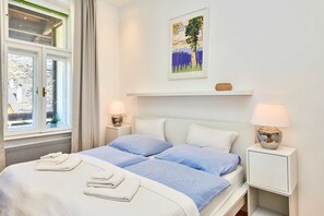 A bedroom with a bed, two bedside tables, a nightstand, a window, and a wall-mounted picture. - Studio Apartment mit Balkon und Raxblick - Top 4 - Landhaus Blauer Spatz (Reichenau an der Rax)