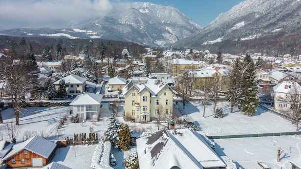 Une ville recouverte de neige, avec des maisons et des montagnes en arrière-plan.