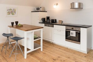 A modern kitchen with white cabinetry, a wooden countertop, a built-in oven, and a microwave. - Superior Familien-apartment mit Bergblick - Top 6 - Landhaus Blauer Spatz (Reichenau an der Rax)