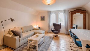 Een woonkamer met een bank, salontafel, fauteuil en eettafel.