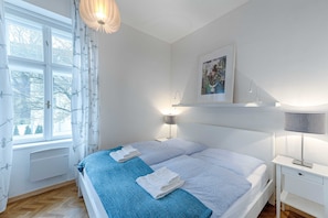 A bedroom with a bed, bedside table, lamp, and a window with curtains. - Superior Familien-apartment mit Bergblick - Top 6 - Landhaus Blauer Spatz (Reichenau an der Rax)