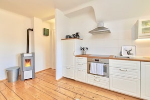 A modern kitchen with white cabinetry, a built-in oven, a stove, and a stainless steel sink. - Superior Apartment mit Raxblick - Top 7 - Landhaus Blauer Spatz (Reichenau an der Rax)