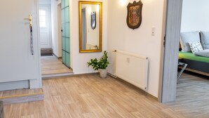 A modern apartment with a wooden floor, a radiator, a green sliding door, a mirror, and a bed with pillows. - Duggis Feriendomizil - Ferienwohnung (Wolgast)