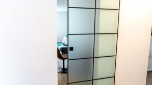 A room with a sliding glass partition, a bed with a green blanket, and a chair. - Duggis Feriendomizil - Ferienwohnung (Wolgast)
