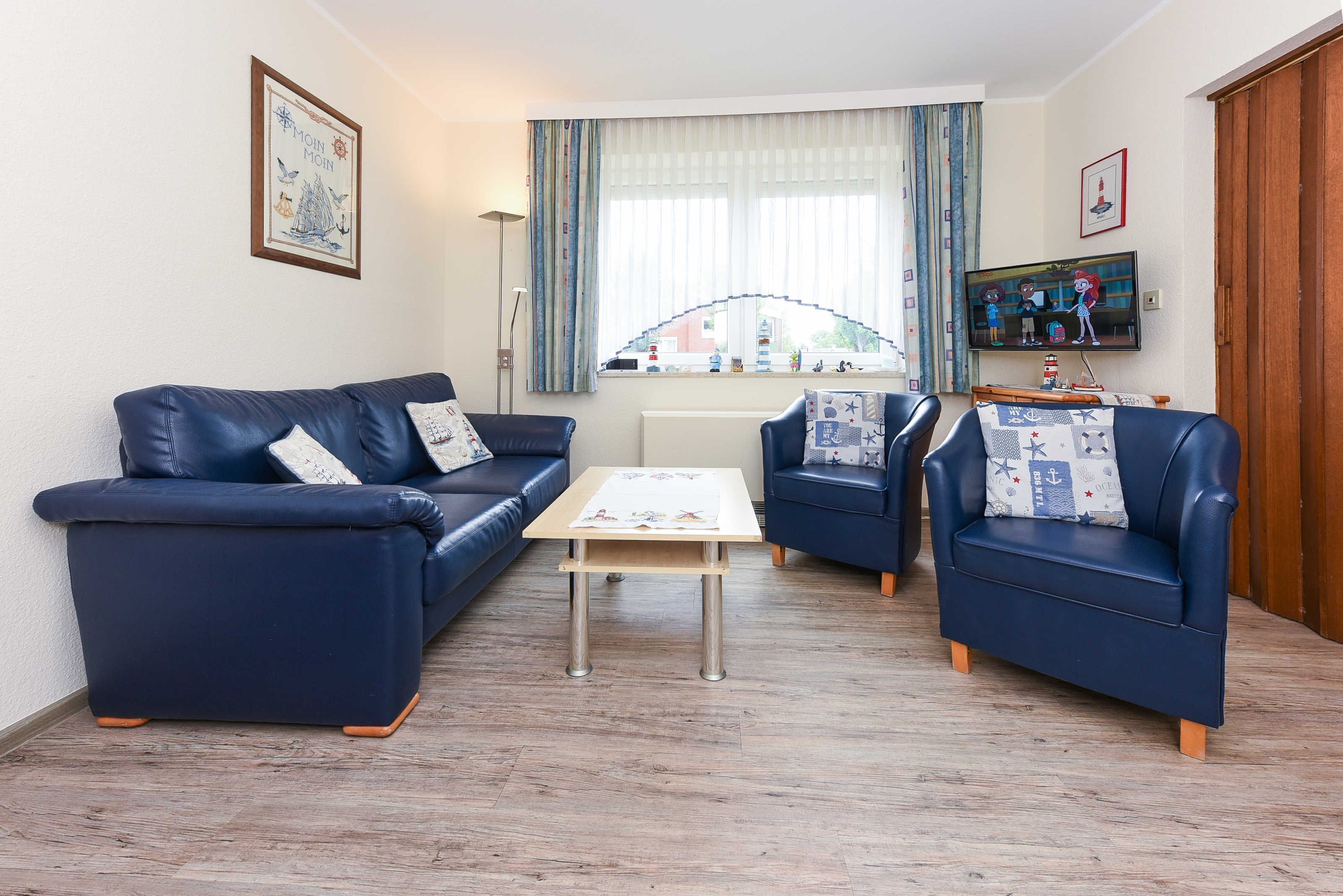 A living room with a blue sofa set, a coffee table, and a television.