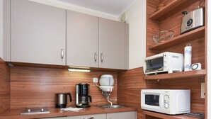 Een compacte keuken met houten kastjes, een koffiezetapparaat, een magnetron en een broodrooster.