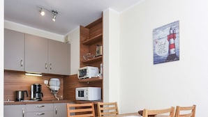 Een kleine keuken met houten kastjes, een magnetron en een koffiezetapparaat.